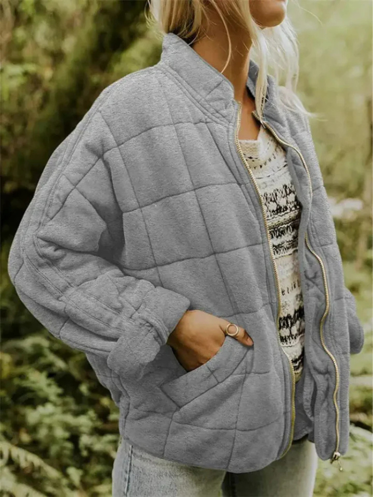 Grijze gewatteerde oversized jas met rits, gedragen door vrouw buiten | Boutique Moda