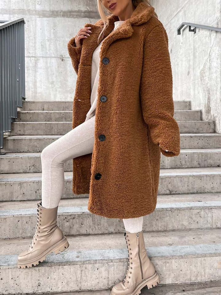 Kameelkleurige lange teddy jas met knopen, gedragen door vrouw op trap | Boutique Moda