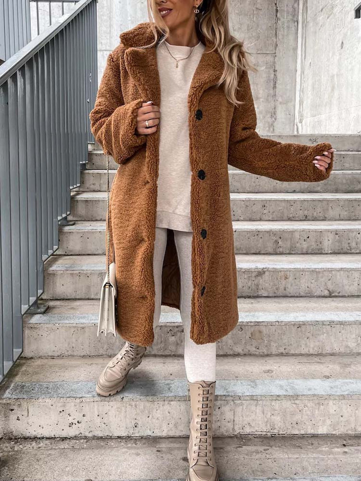 Vrouw draagt lange camel teddy jas met witte trui en veterlaarzen | Boutique Moda