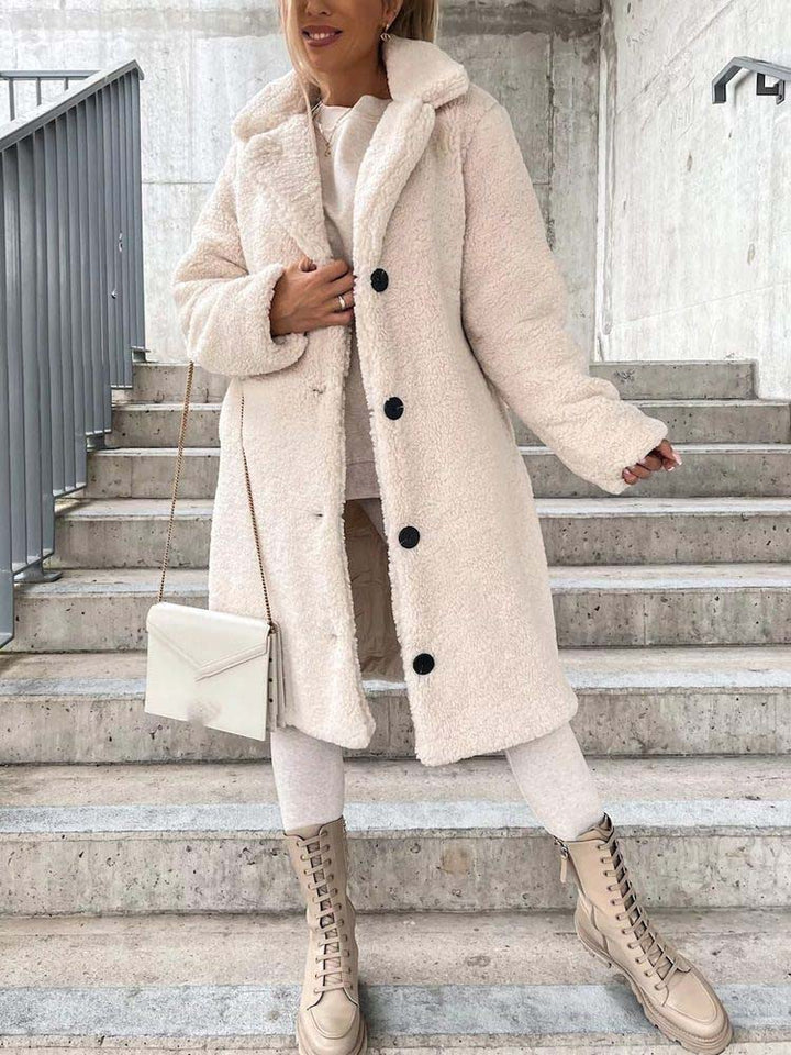 Beige lange teddy jas met knopen, gedragen door vrouw op trap | Boutique Moda