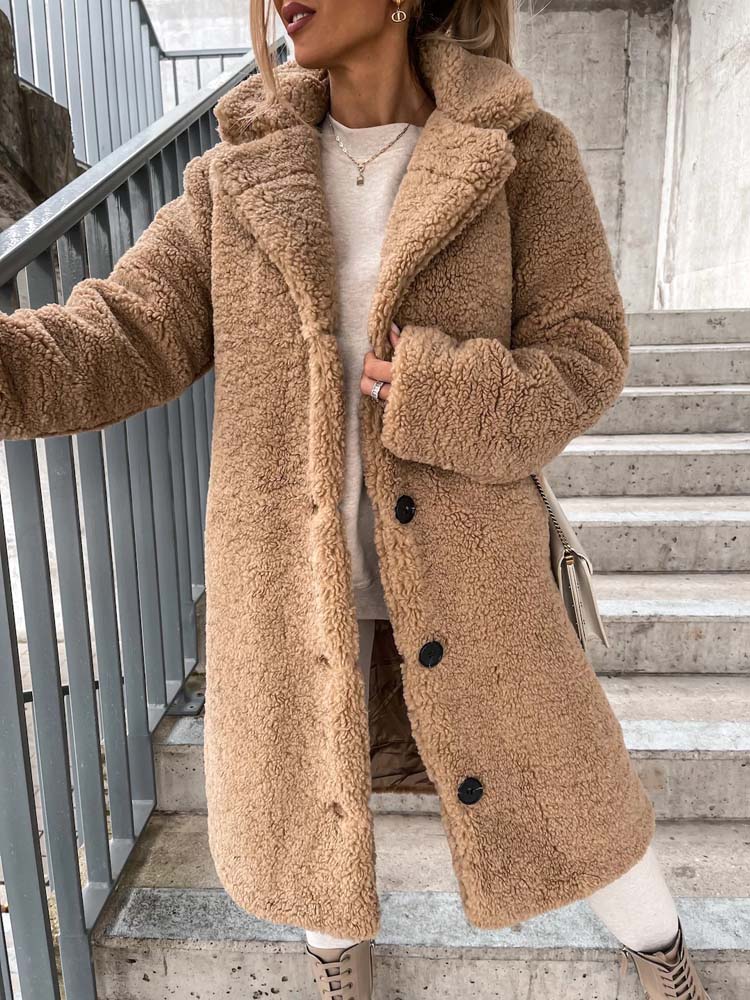 Beige lange teddy jas met revers, gedragen door vrouw op trap | Boutique Moda